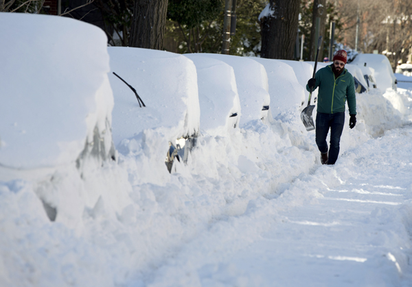 Ben Osborn walks with a shovel past a line of snowed-in cars on a Steet in northeast Washington, on Sunday (AP photo)